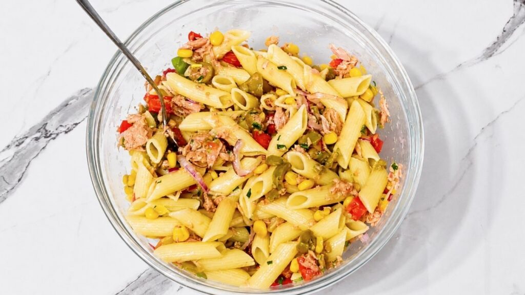 Quick and easy tuna pasta salad with corn, tomatoes, olives, and red onion