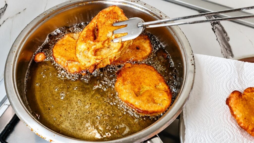 Breaded eggplant slices frying in hot oil until golden brown.