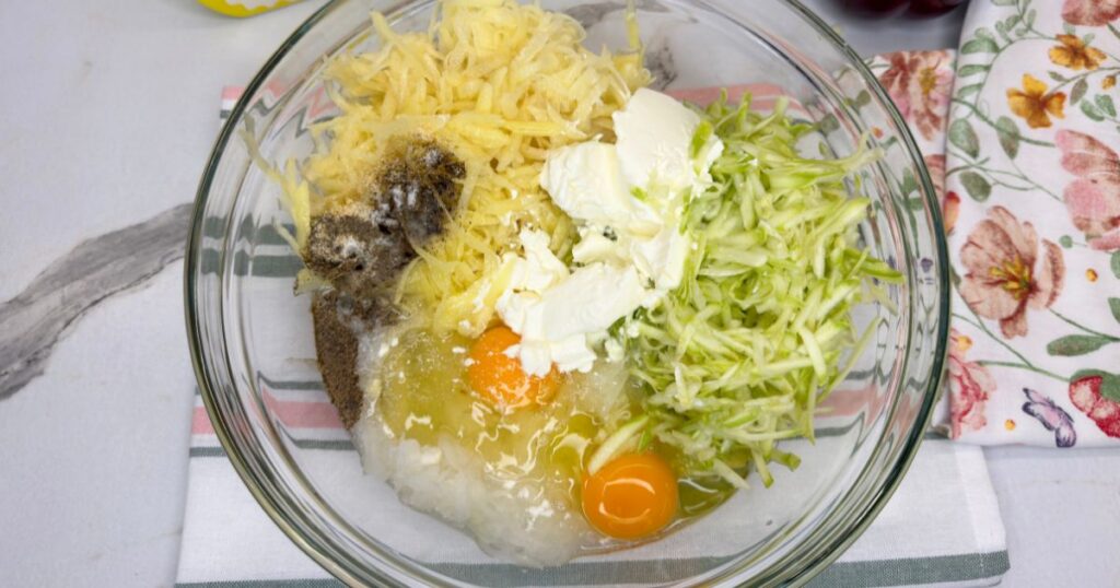 All ingredients for zucchini and potato slice combined in a large mixing bowl