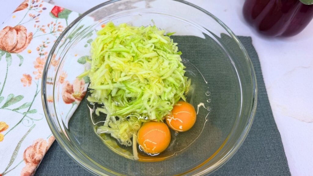 Whisking eggs, vegetable oil, and freshly grated zucchini together in a large glass mixing bowl for Moist Chocolate Zucchini bread batter.