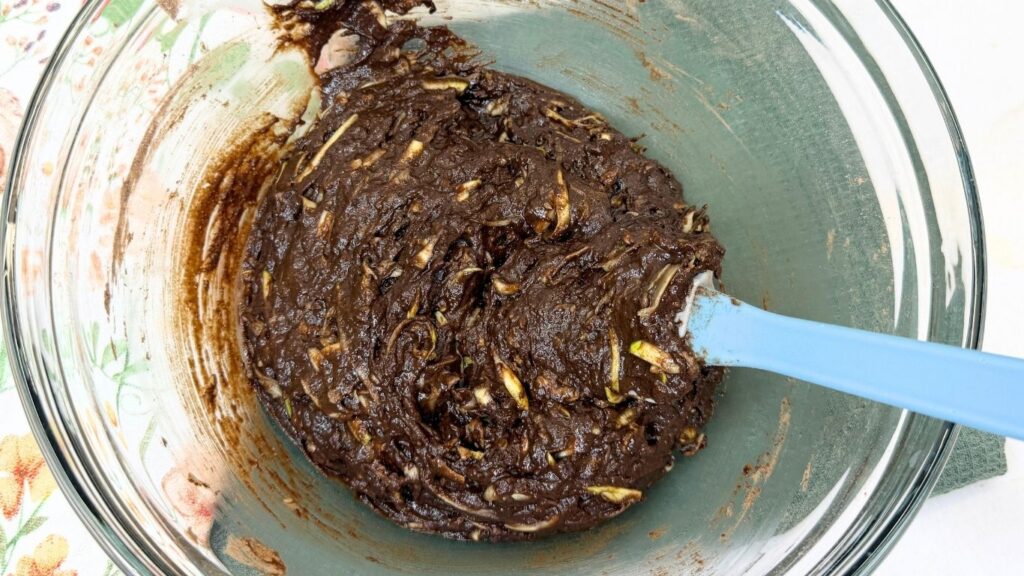 A thick, smooth chocolate batter with visible chocolate chunks fully combined in a bowl, ready to be baked into Moist Chocolate Zucchini bread.