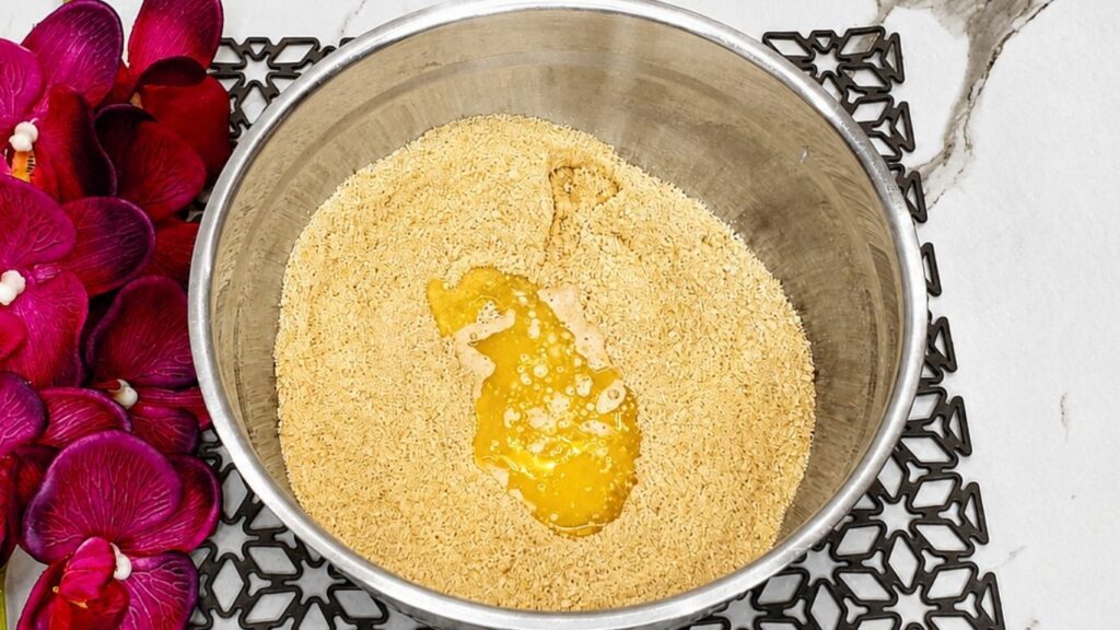 Crushed biscuit mixture with milk and melted butter in a bowl for no-bake peach yogurt cake crust.