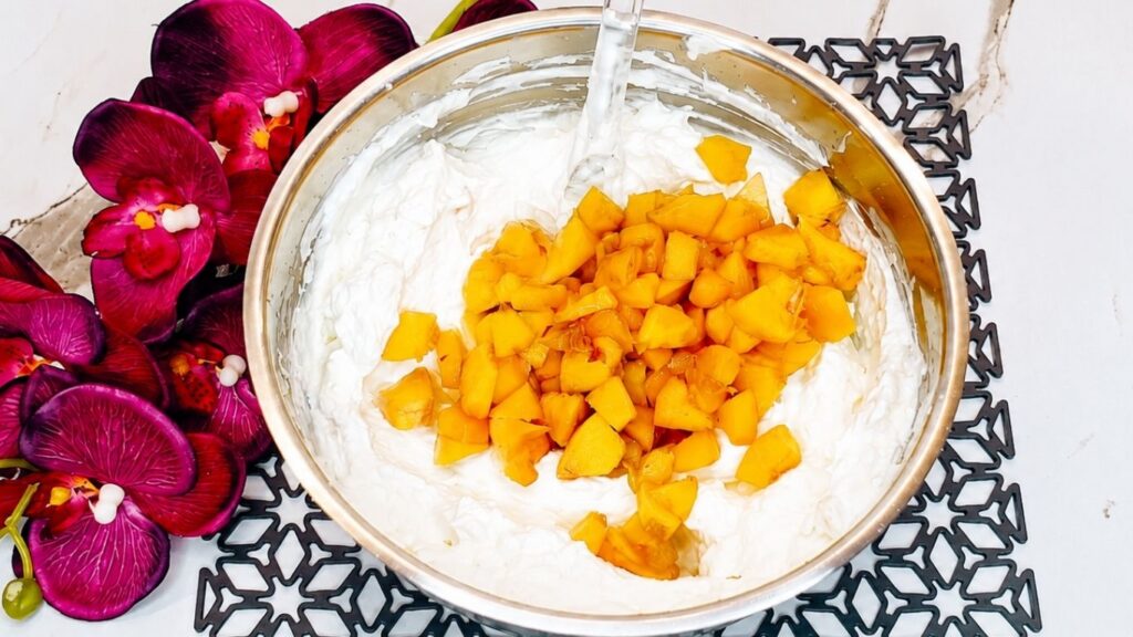 Fresh chopped peaches mixed with peach yogurt and whipped cream for easy no-bake peach yogurt cake filling.