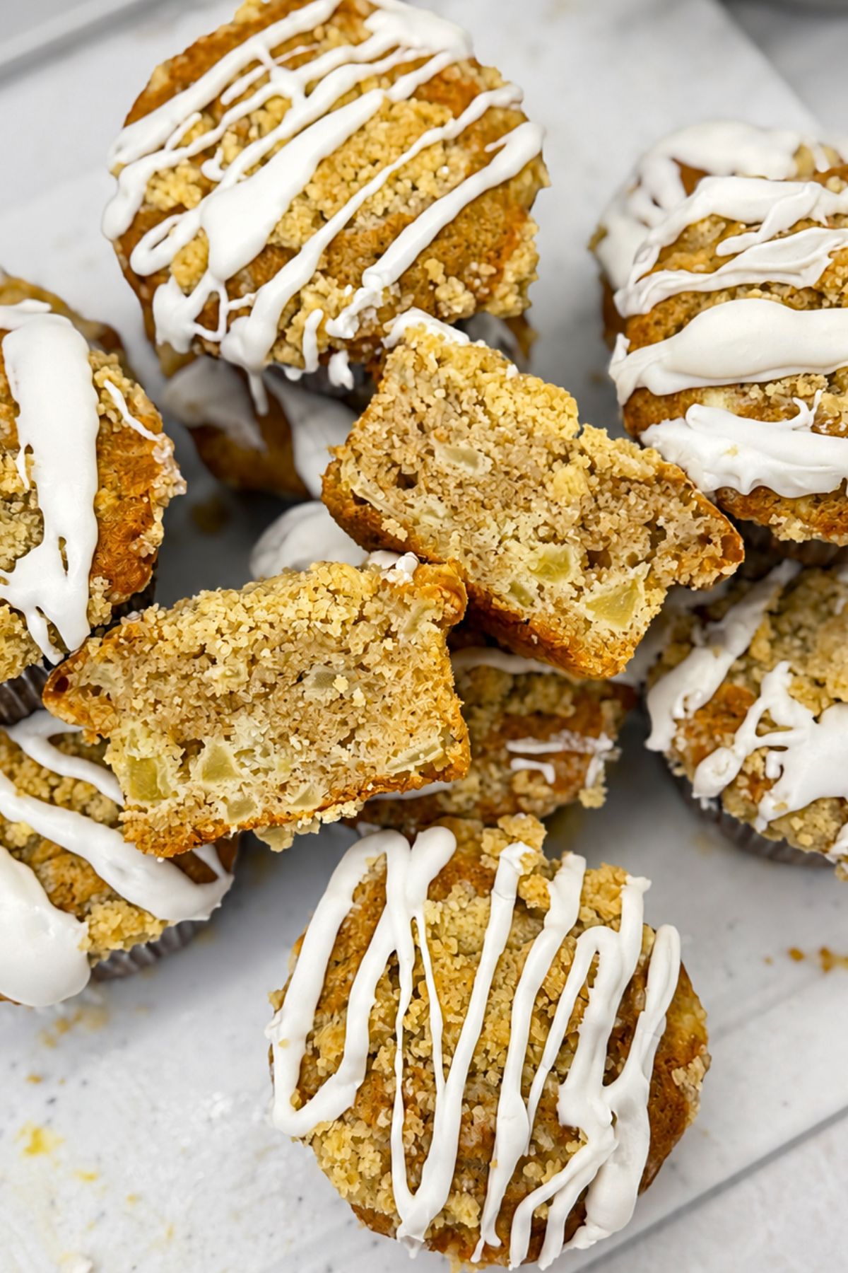 Apple crumb muffins with cinnamon, buttery crumb topping, vanilla icing, and diced apples inside.