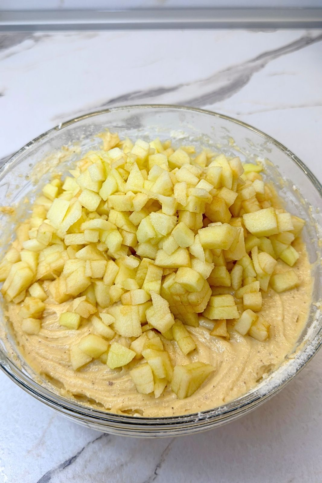 Peeled and diced apples added to cinnamon muffin batter.