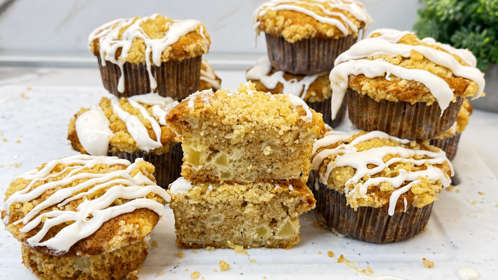 Apple crumb muffins with cinnamon, buttery crumb topping, vanilla icing, and diced apples inside.