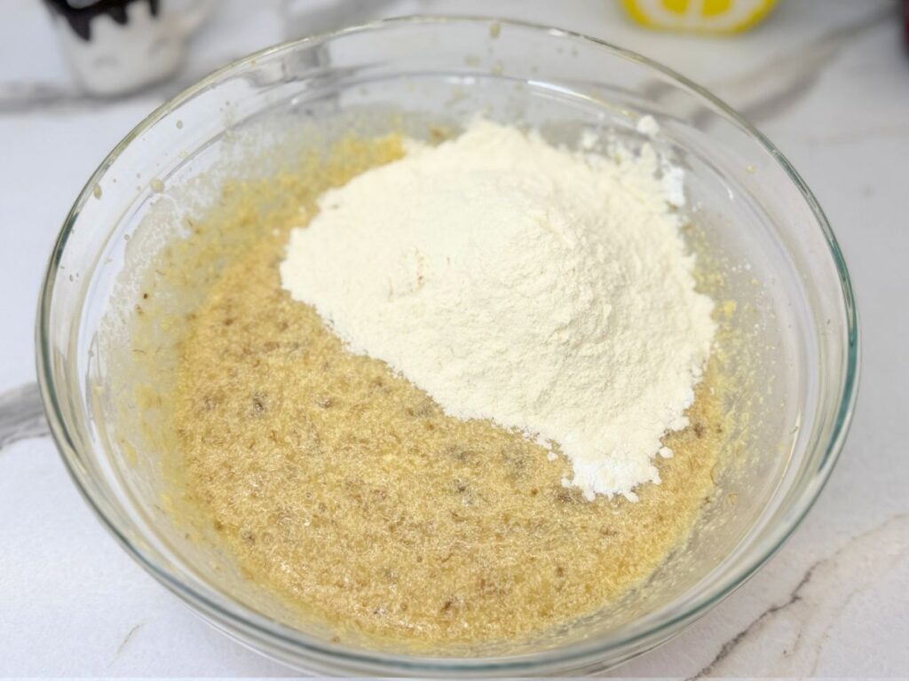 Dry ingredients added to the wet ingredients in a mixing bowl.