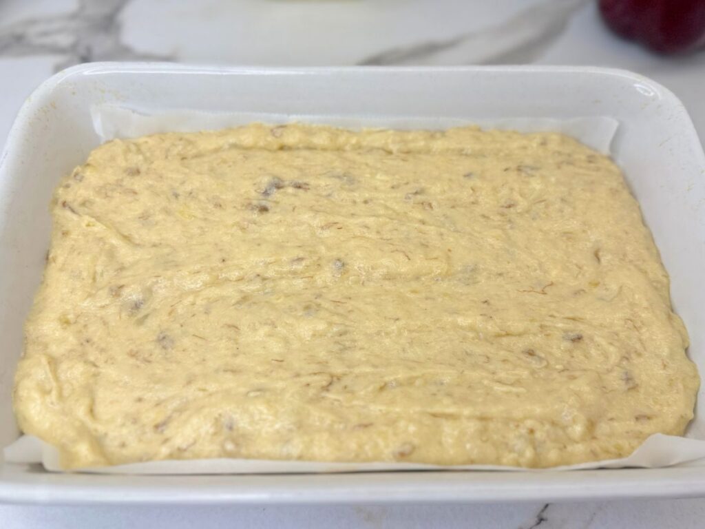 Banana cake batter spread evenly in a baking pan and ready to bake.