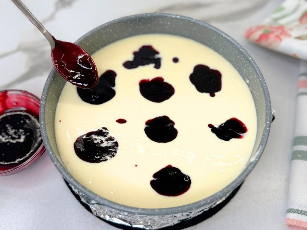 Spoonfuls of homemade blueberry sauce added over the cheesecake filling