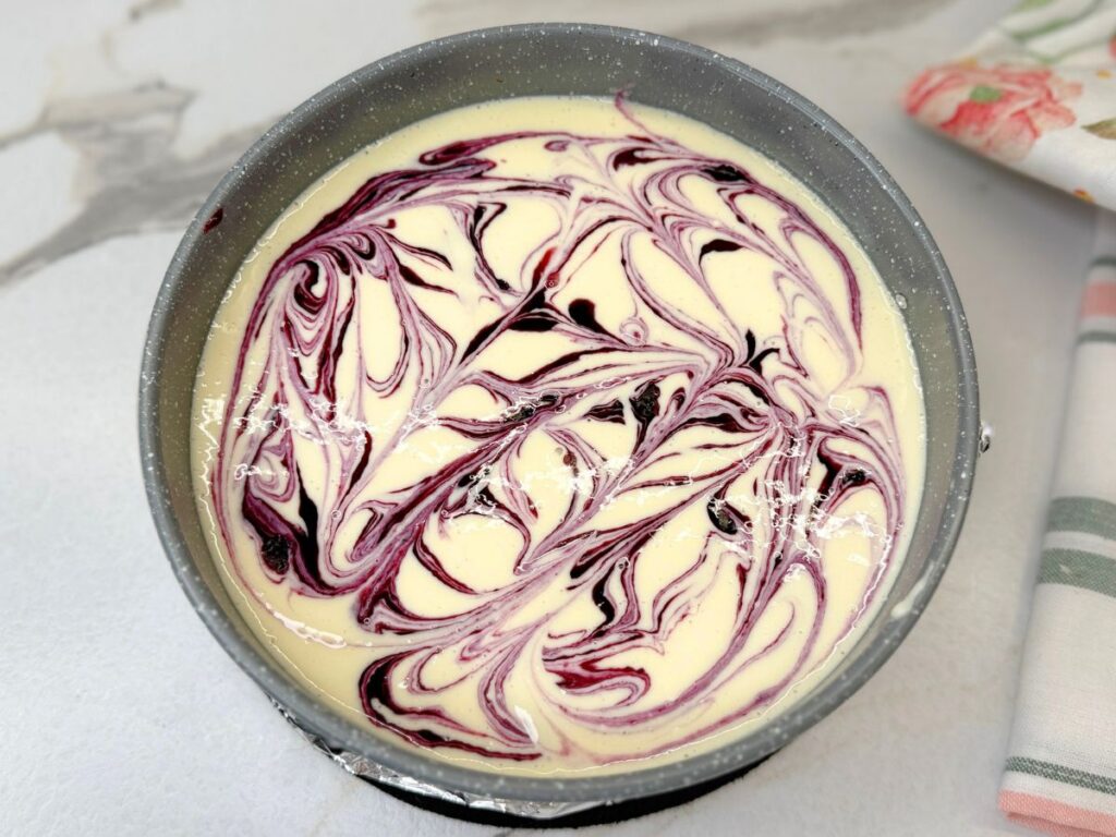 Spoonfuls of homemade blueberry sauce added over the cheesecake filling