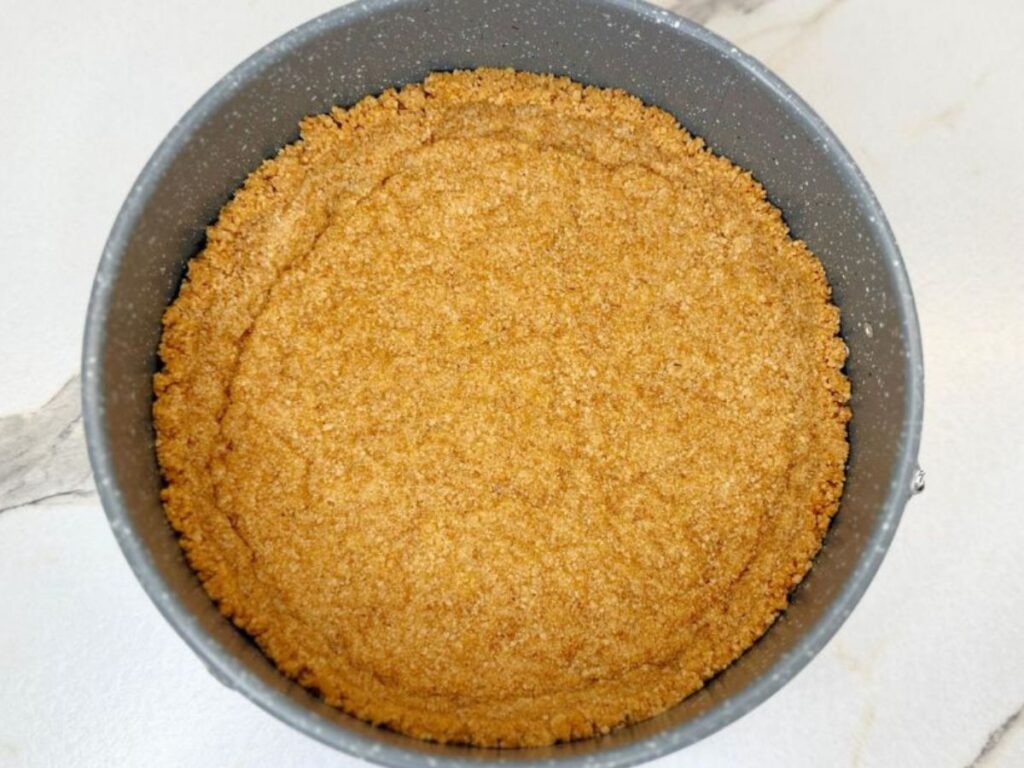 Graham cracker crust pressed evenly into a springform pan