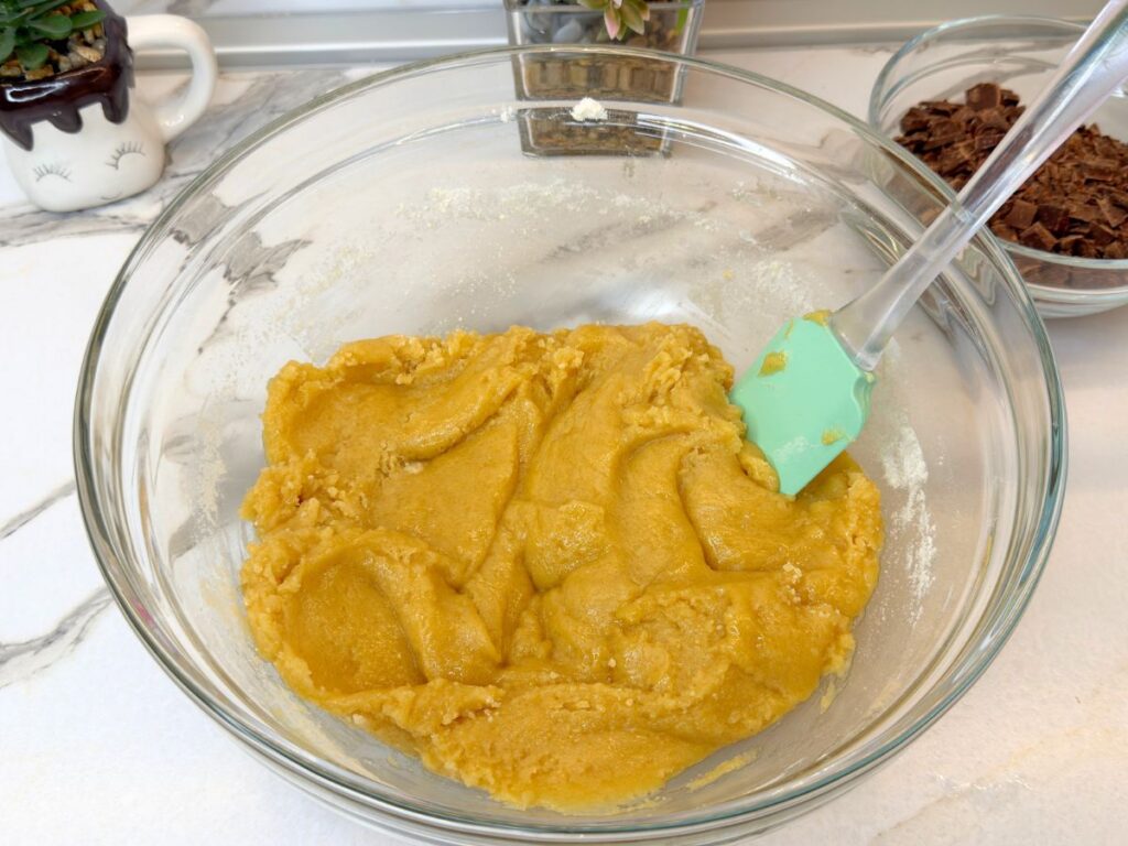 Thick cookie dough mixed in a glass bowl before adding the chocolate chips.