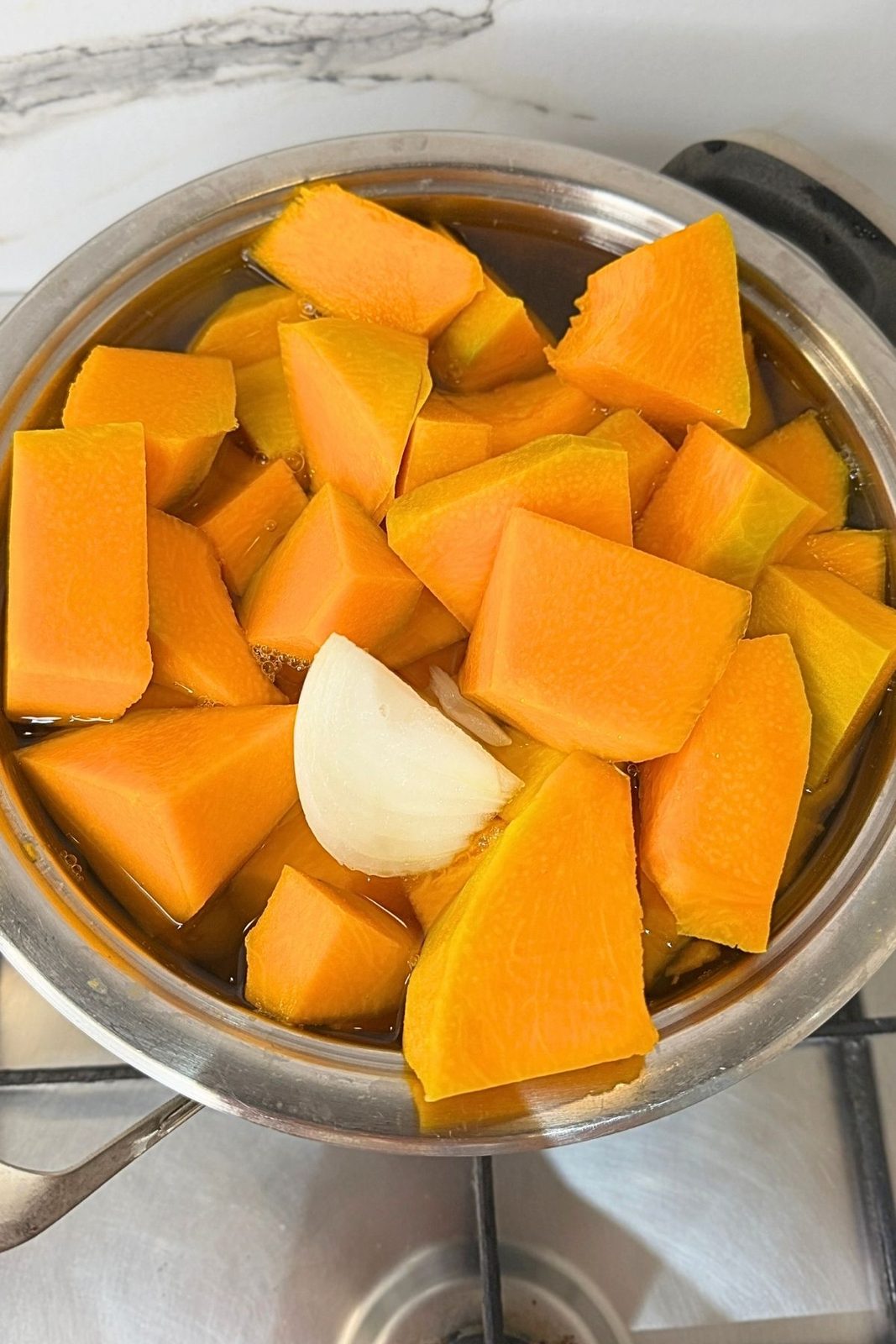 Chopped pumpkin and onion cooking with vegetables in a pot of water