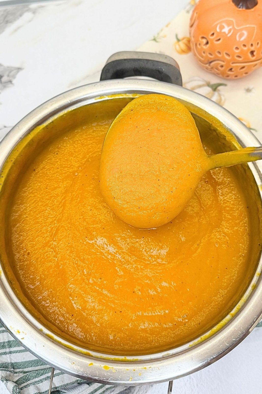 Smooth blended creamy pumpkin soup in a pot with a ladle