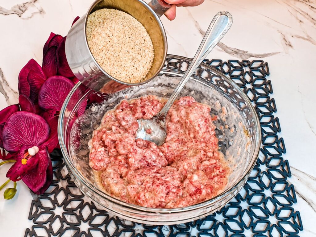 Breadcrumbs being added to the seasoned ground beef mixture