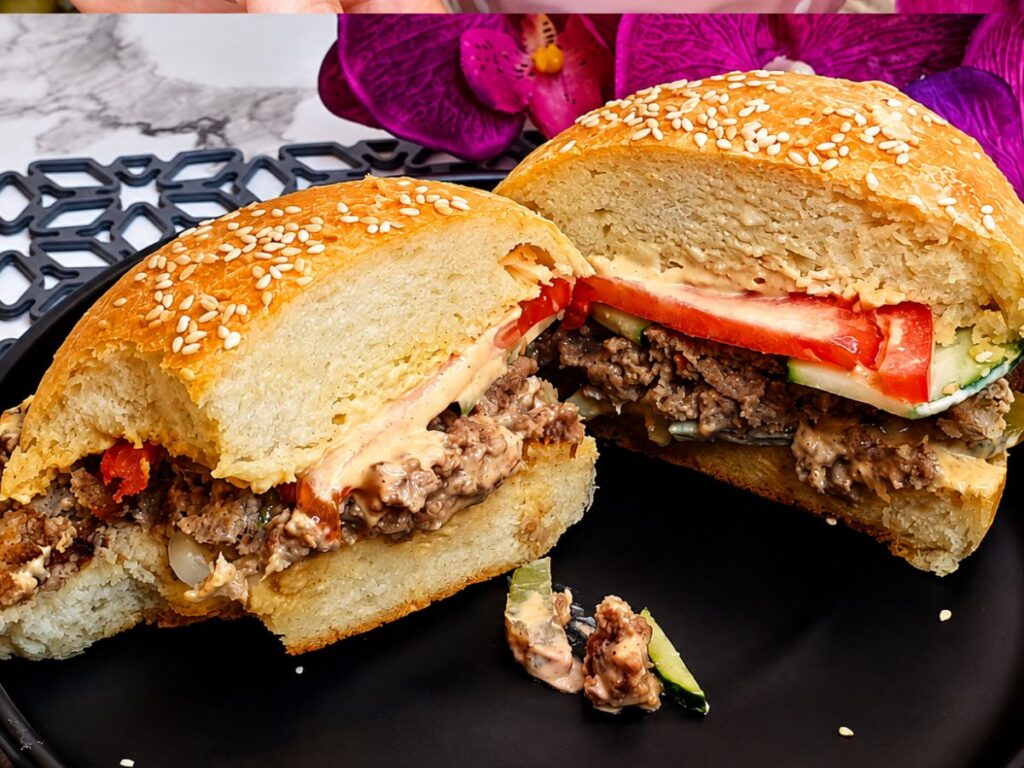Homemade burger cut in half to reveal the patty, sauce, and vegetables