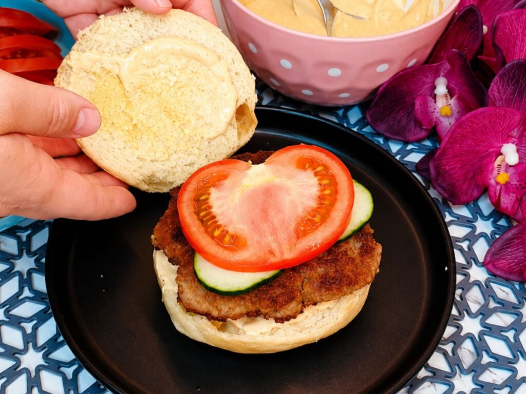 Close-up of a homemade burger with a juicy patty, creamy sauce, and fresh toppings