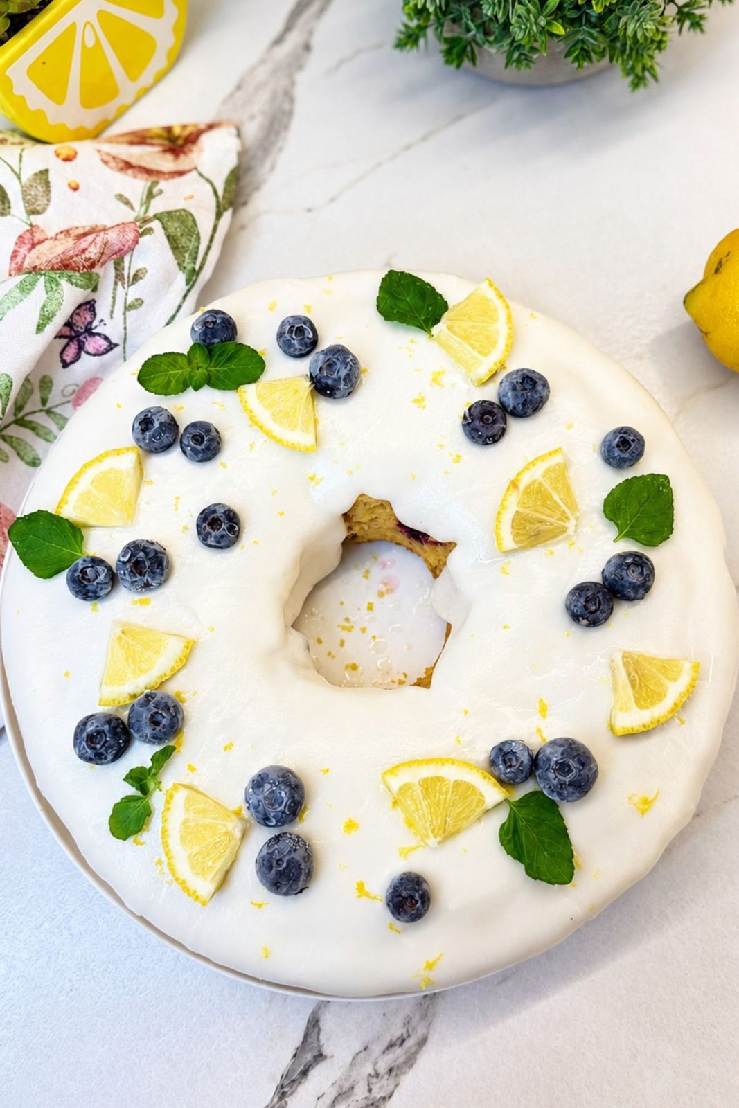 Lemon Blueberry Bundt Cake covered with lemon icing and decorated with blueberries, lemon slices, and mint