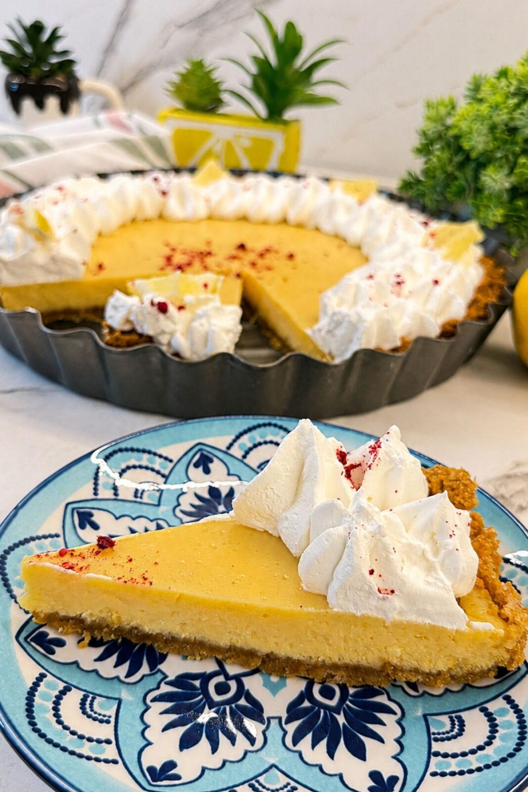 Slice of creamy lemon pie served with whipped cream on a blue patterned plate