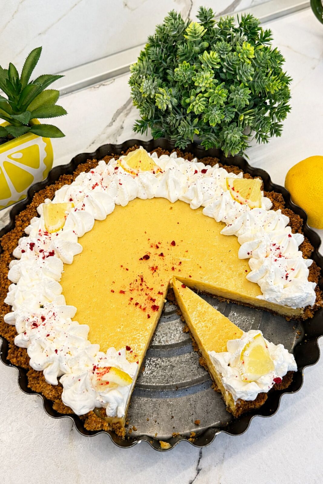 Creamy lemon pie with whipped cream, lemon slices, and a slice ready to serve