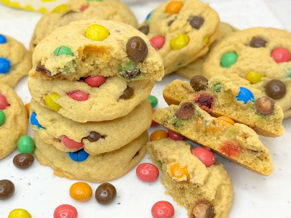 Soft and chewy M&M cookies stacked on a plate and filled with colorful M&M candies.