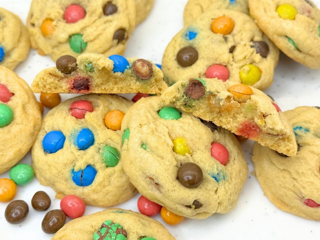 Soft and chewy M&M cookies stacked on a plate and filled with colorful M&M candies.