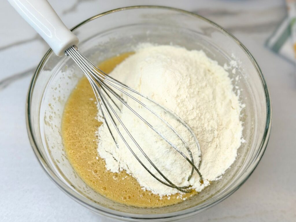 Dry and wet ingredients for M&M cookies prepared in separate mixing bowls.