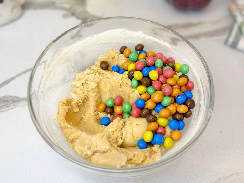 M&M cookie dough mixed with colorful M&M candies in a bowl.