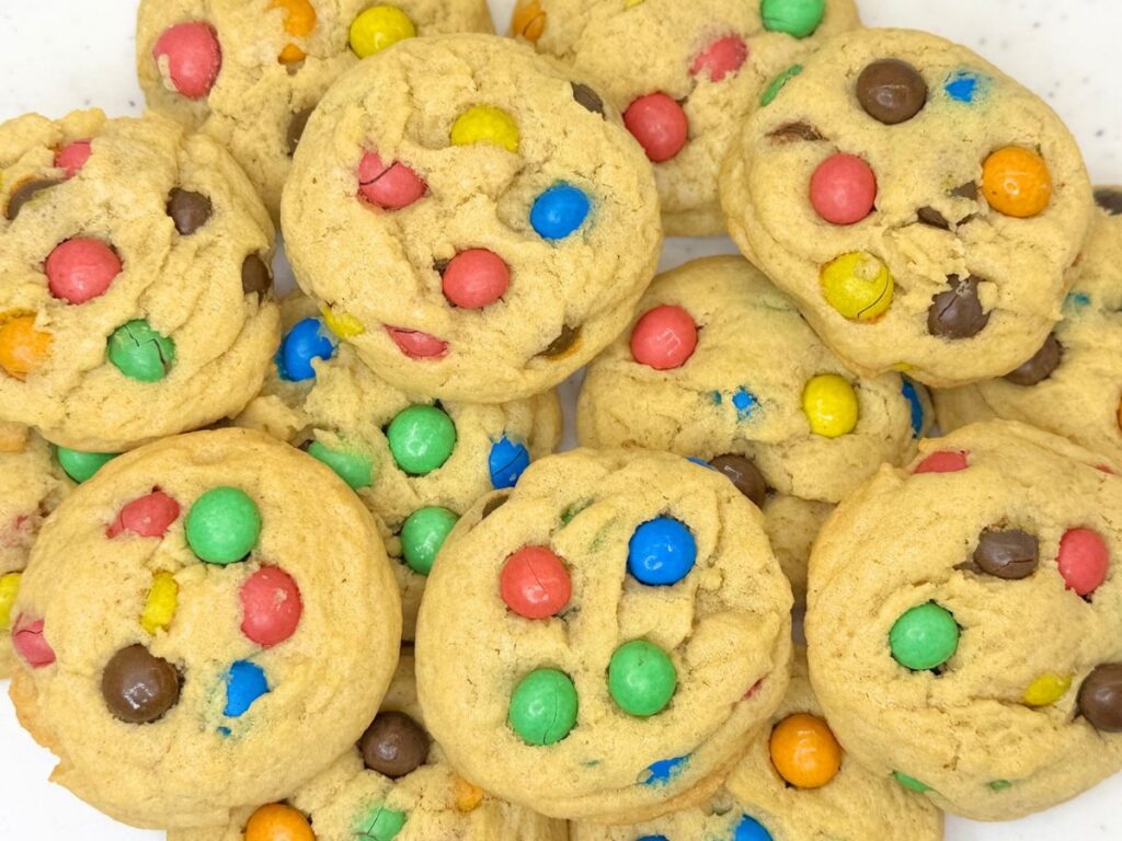 Soft and chewy M&M cookies stacked on a plate and filled with colorful M&M candies.