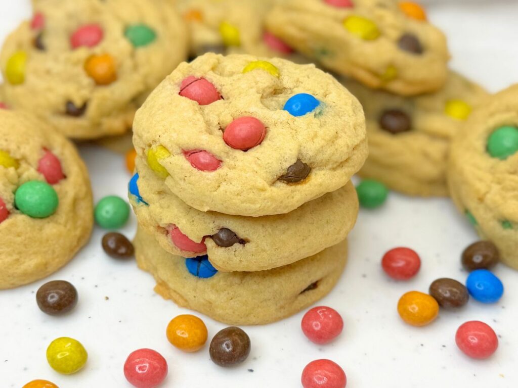 Soft and chewy M&M cookies stacked on a plate and filled with colorful M&M candies.