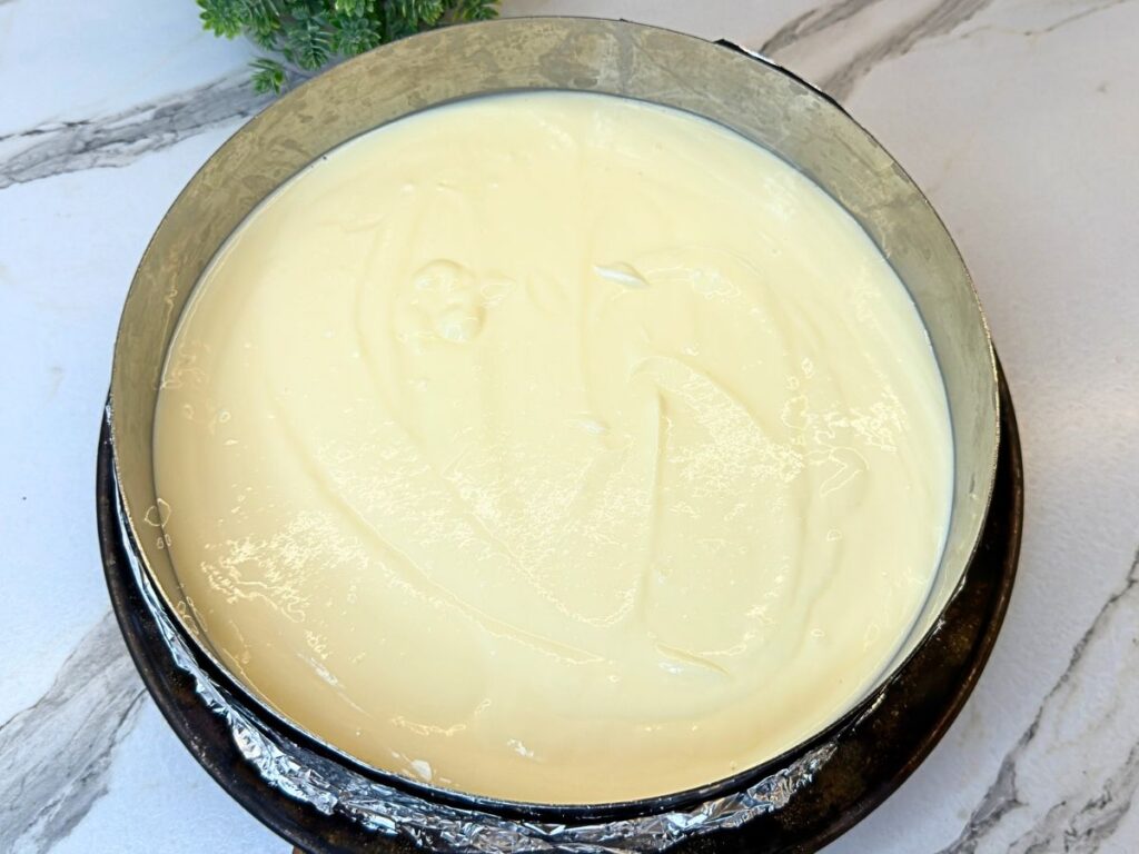 Smooth cheesecake filling poured over the cookie crust in a springform pan