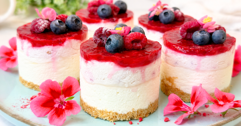 No-bake mini cheesecakes with creamy filling, mixed berry topping, fresh raspberries, and blueberries.