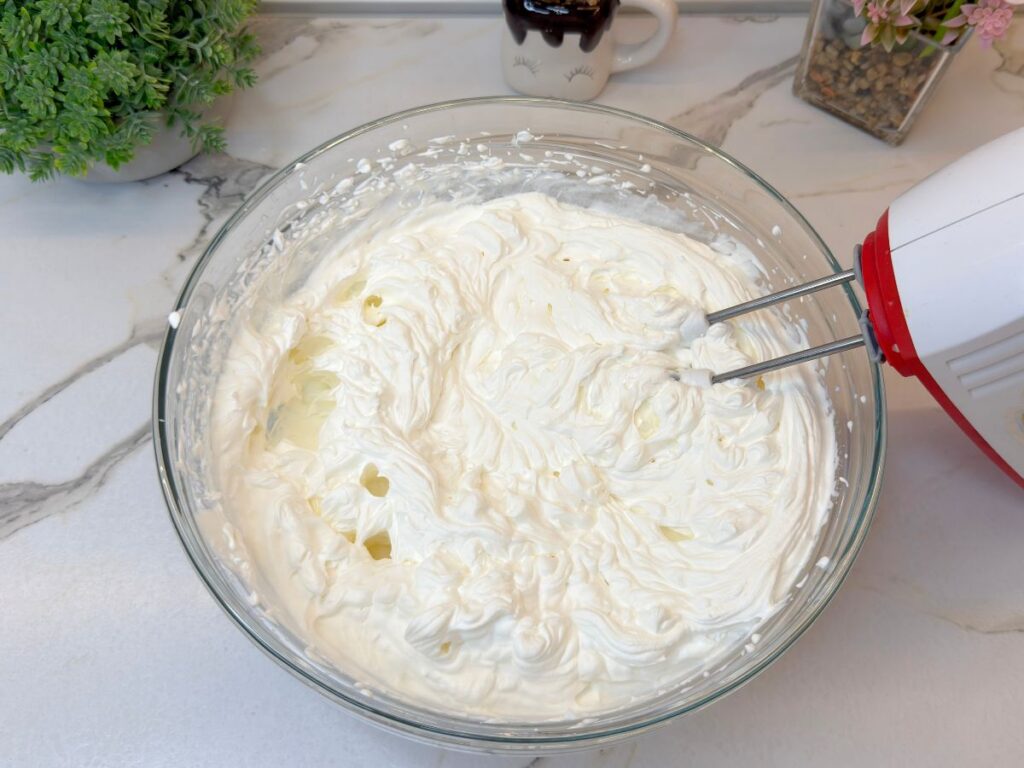 Heavy whipping cream beaten until thick and fluffy in a glass mixing bowl.