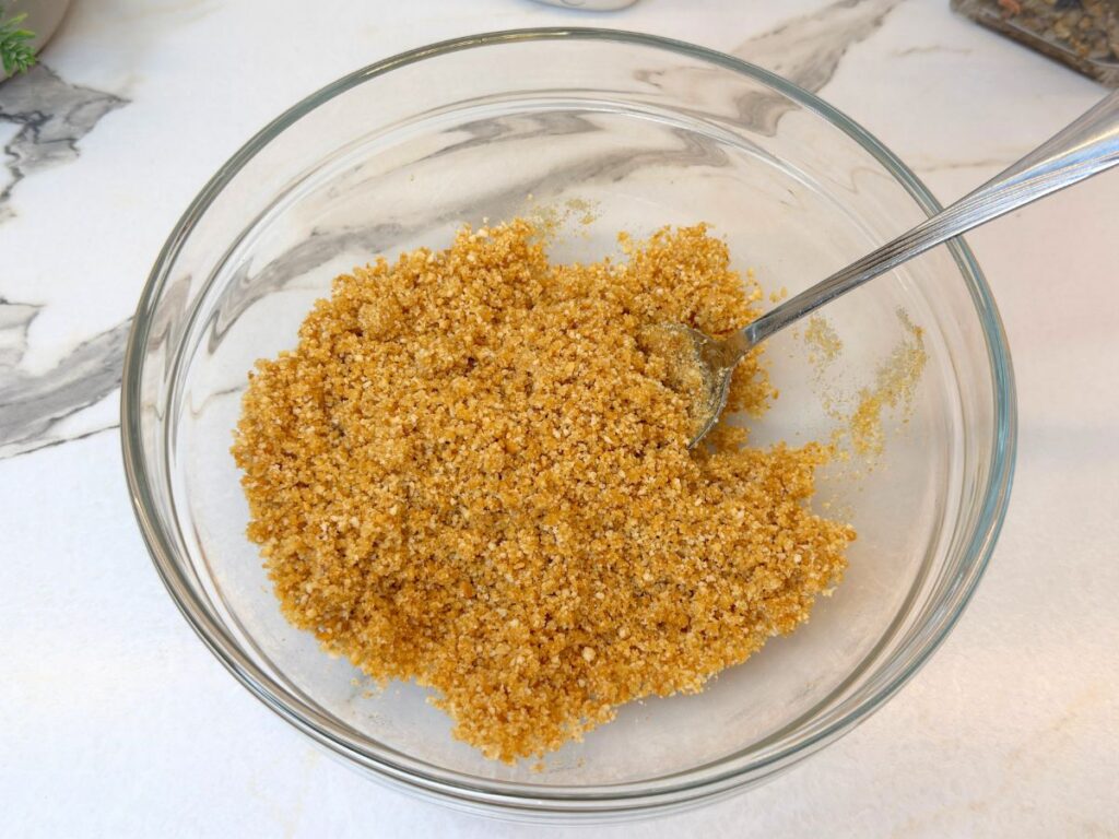 Graham cracker crumbs combined with melted butter for the cheesecake crust.