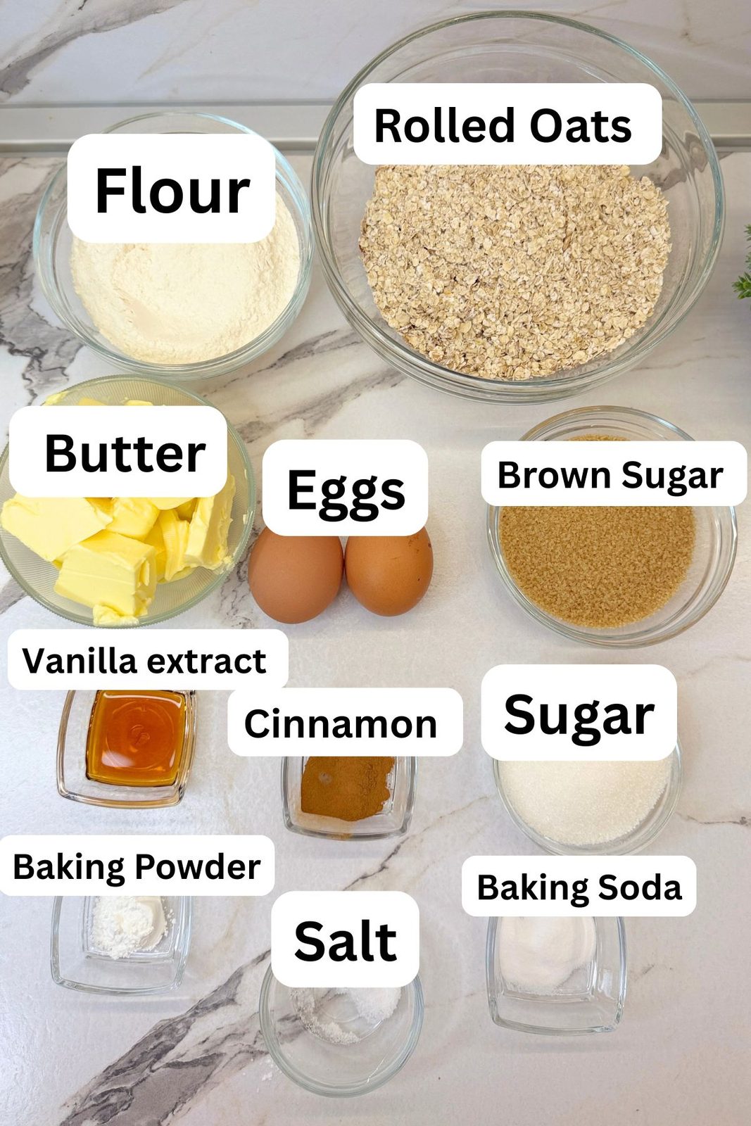 Ingredients for homemade oatmeal cream pies, including rolled oats, flour, butter, eggs, sugar, vanilla, cinnamon, and leavening agents