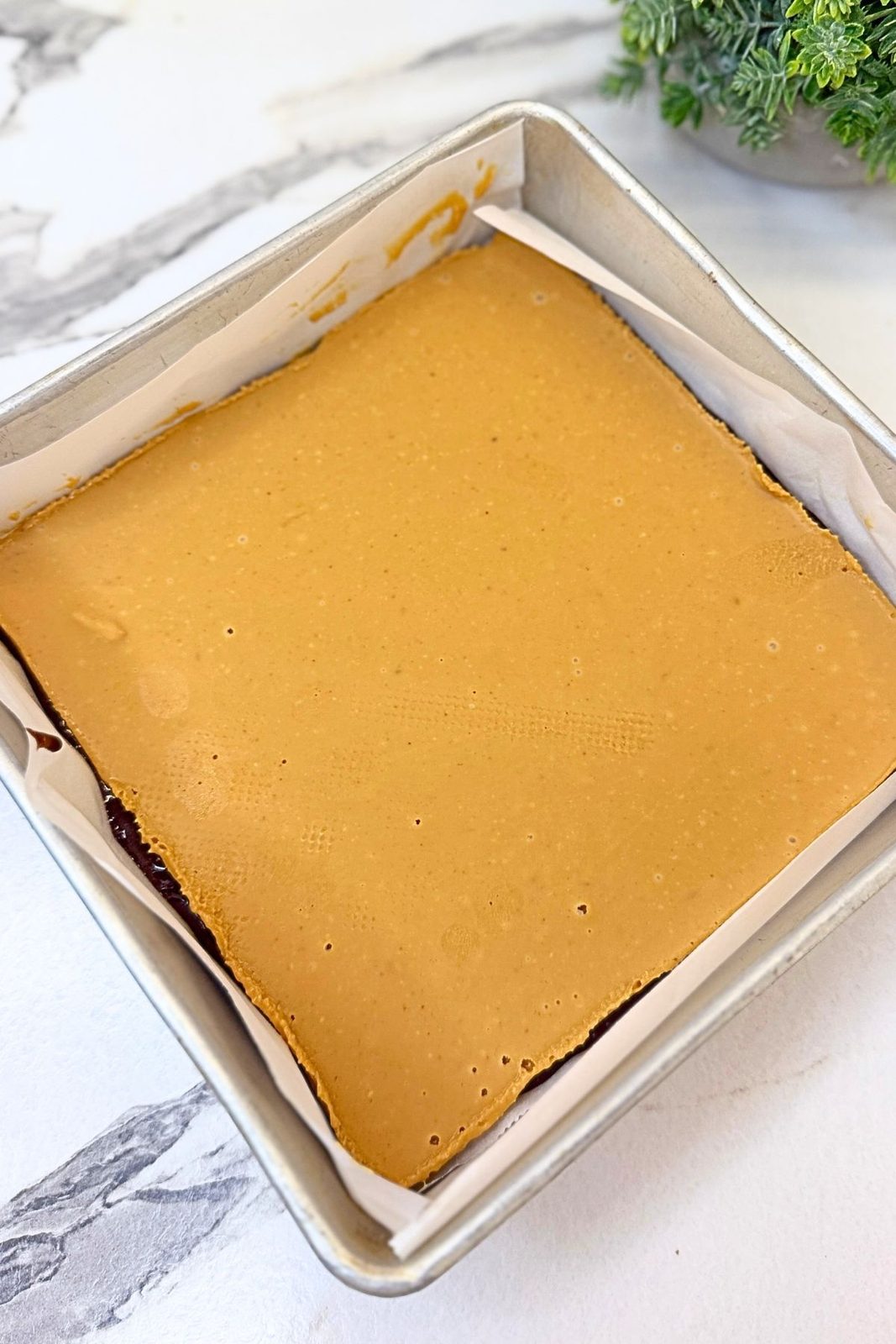 Frozen peanut butter sheet placed over the first layer of chocolate brownie batter.