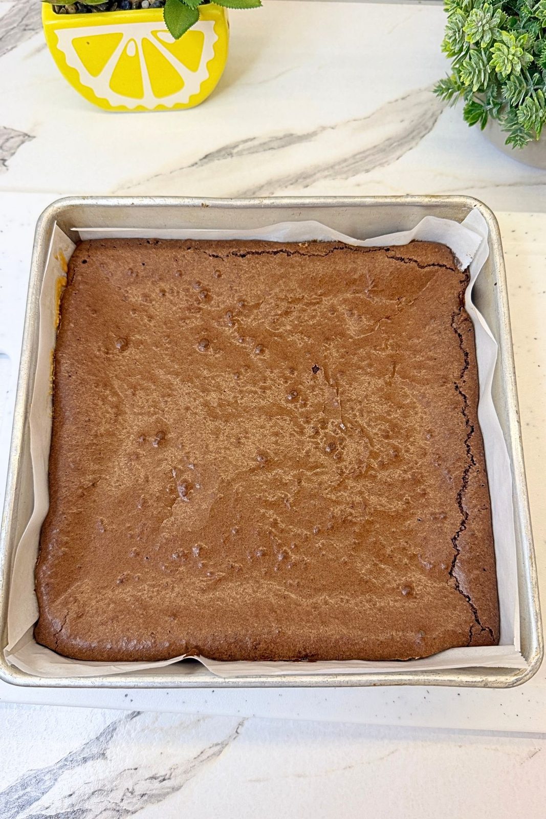 Freshly baked peanut butter brownie cooling in a parchment-lined square baking pan.