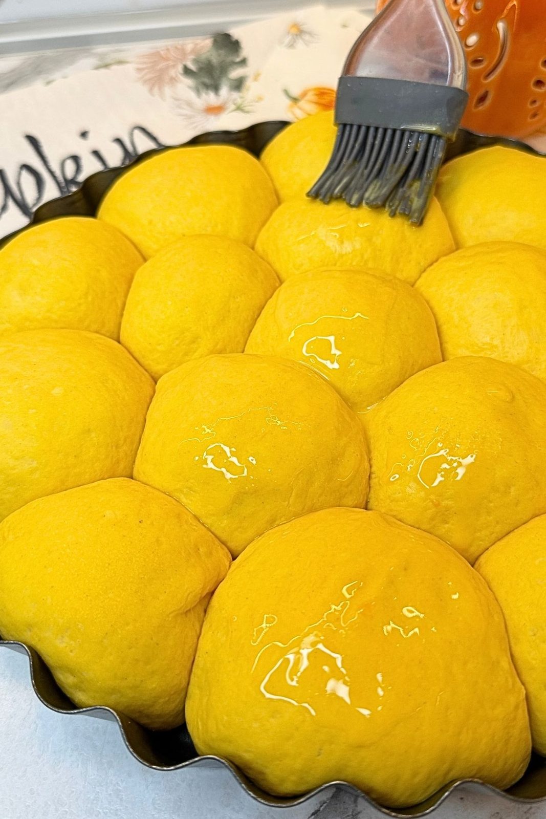 Brushing the risen Pumpkin Dinner Rolls with egg yolk and milk