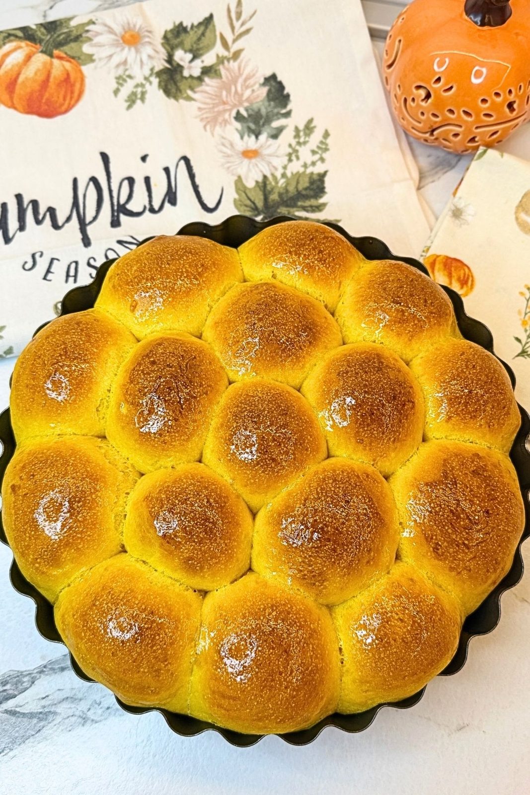 Freshly baked golden Pumpkin Dinner Rolls in a round pan