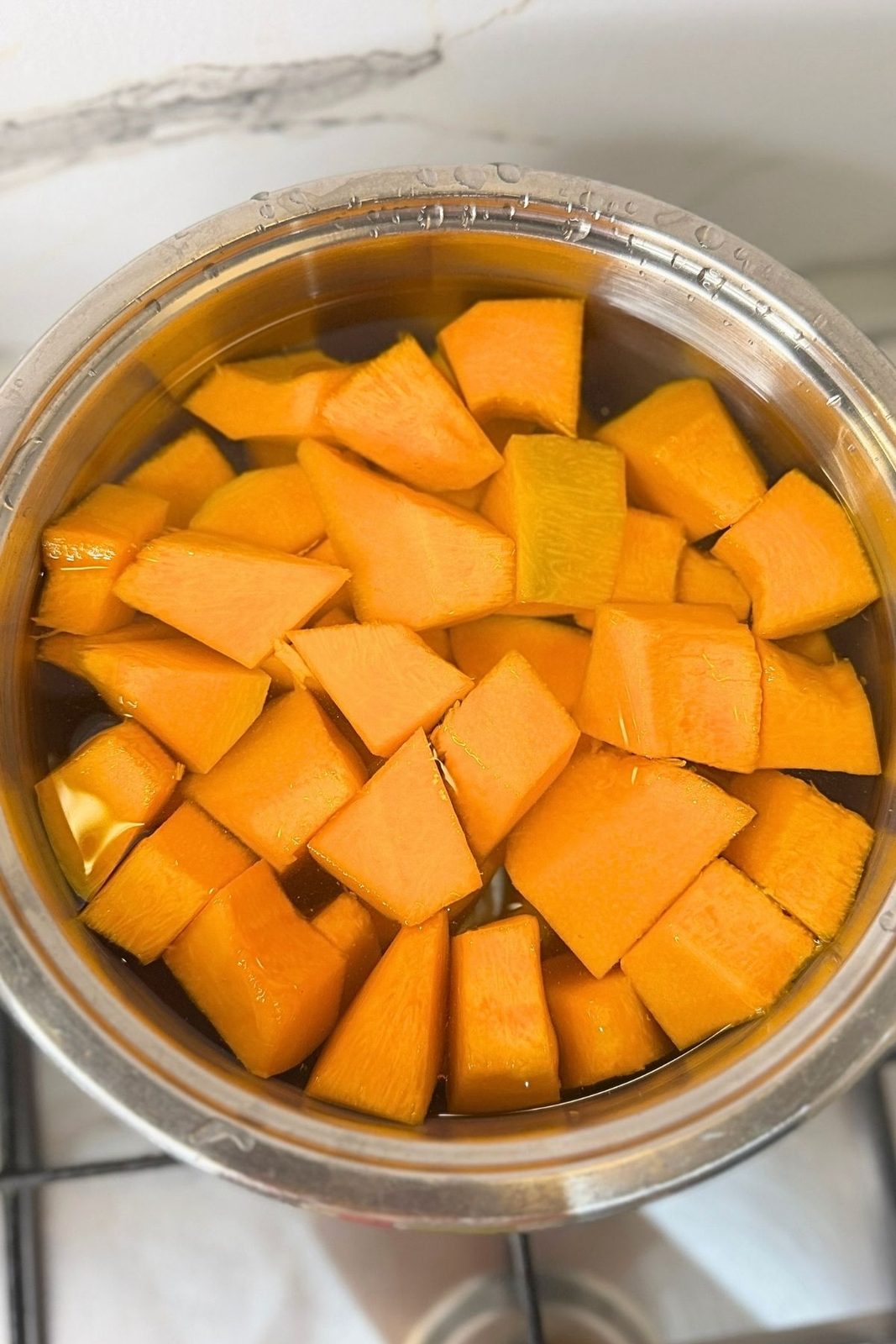 Fresh pumpkin cubes covered with water in a pot before cooking
