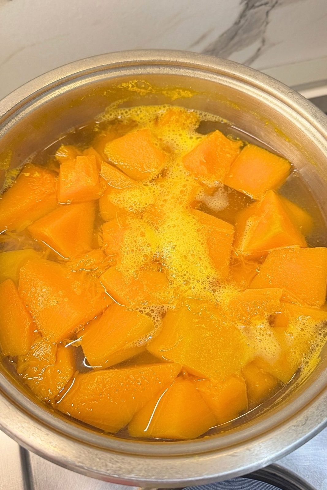 Fresh pumpkin pieces cooking in water until soft and tender