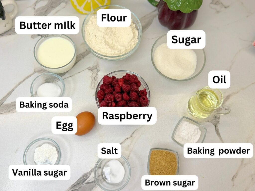 Ingredients for homemade raspberry bread with fresh raspberries and vanilla icing arranged on a table.