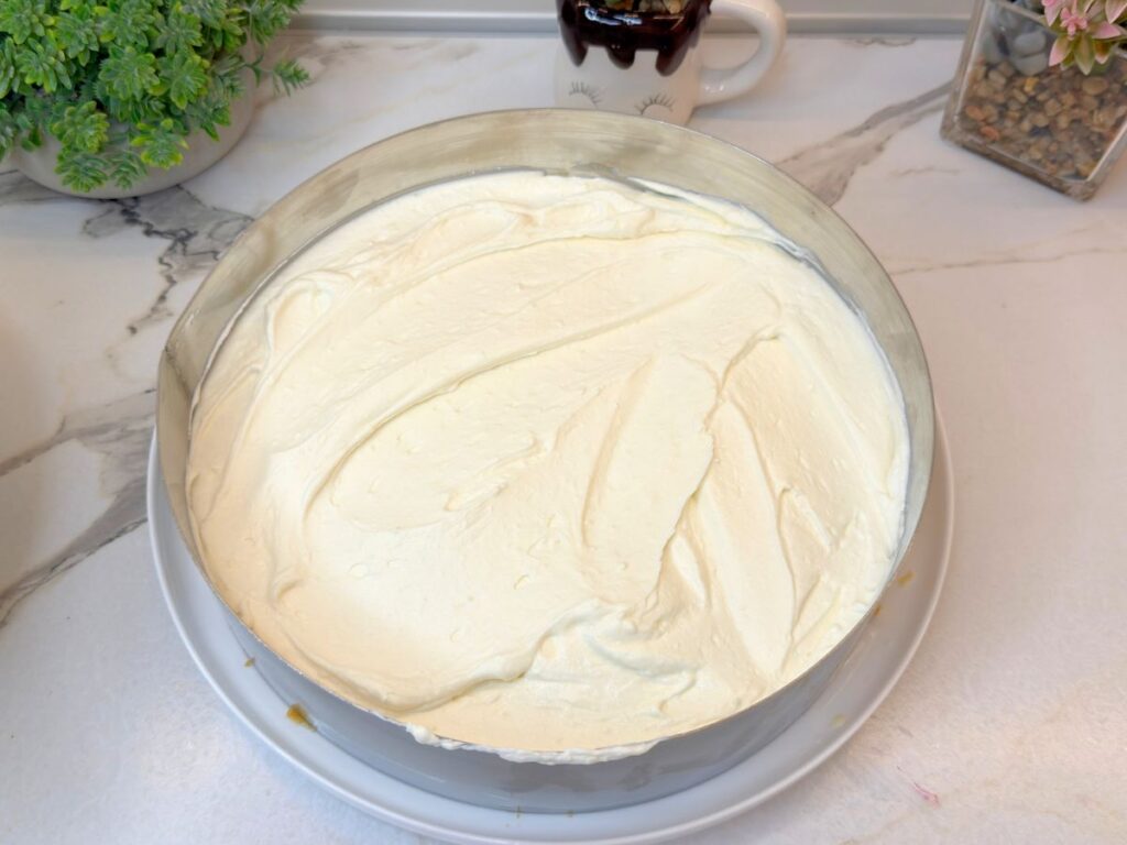 First layer of cream cheese filling spread evenly over the vanilla sponge cake base