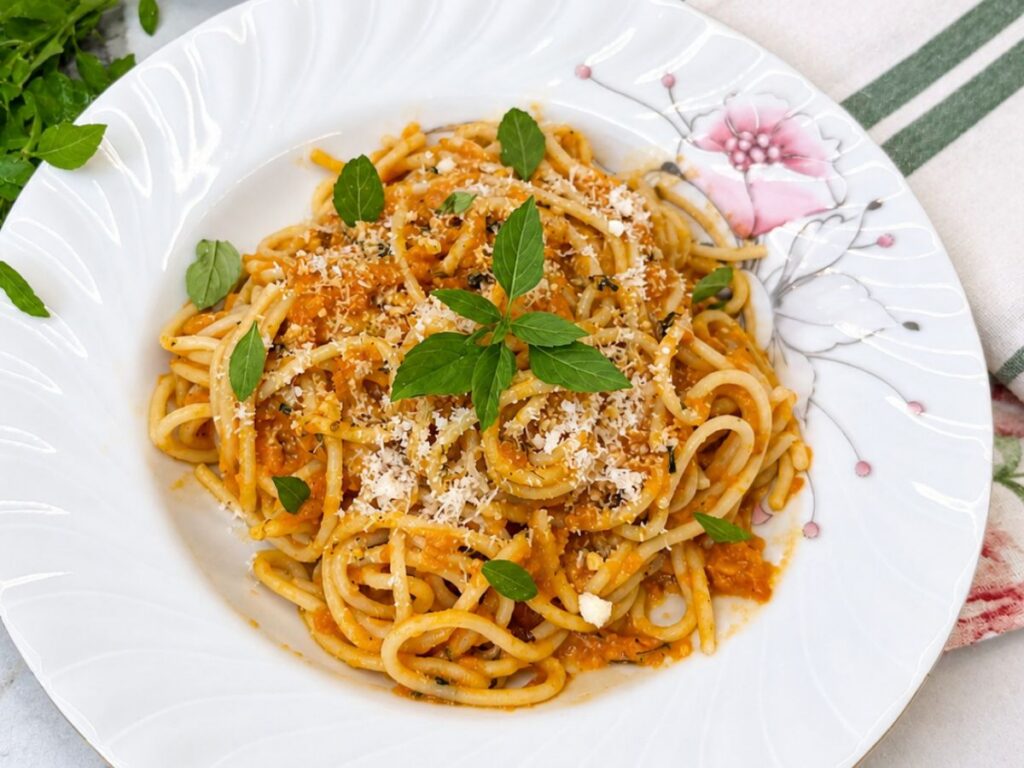 Roasted Tomato Pasta topped with grated Parmesan cheese and fresh basil leaves