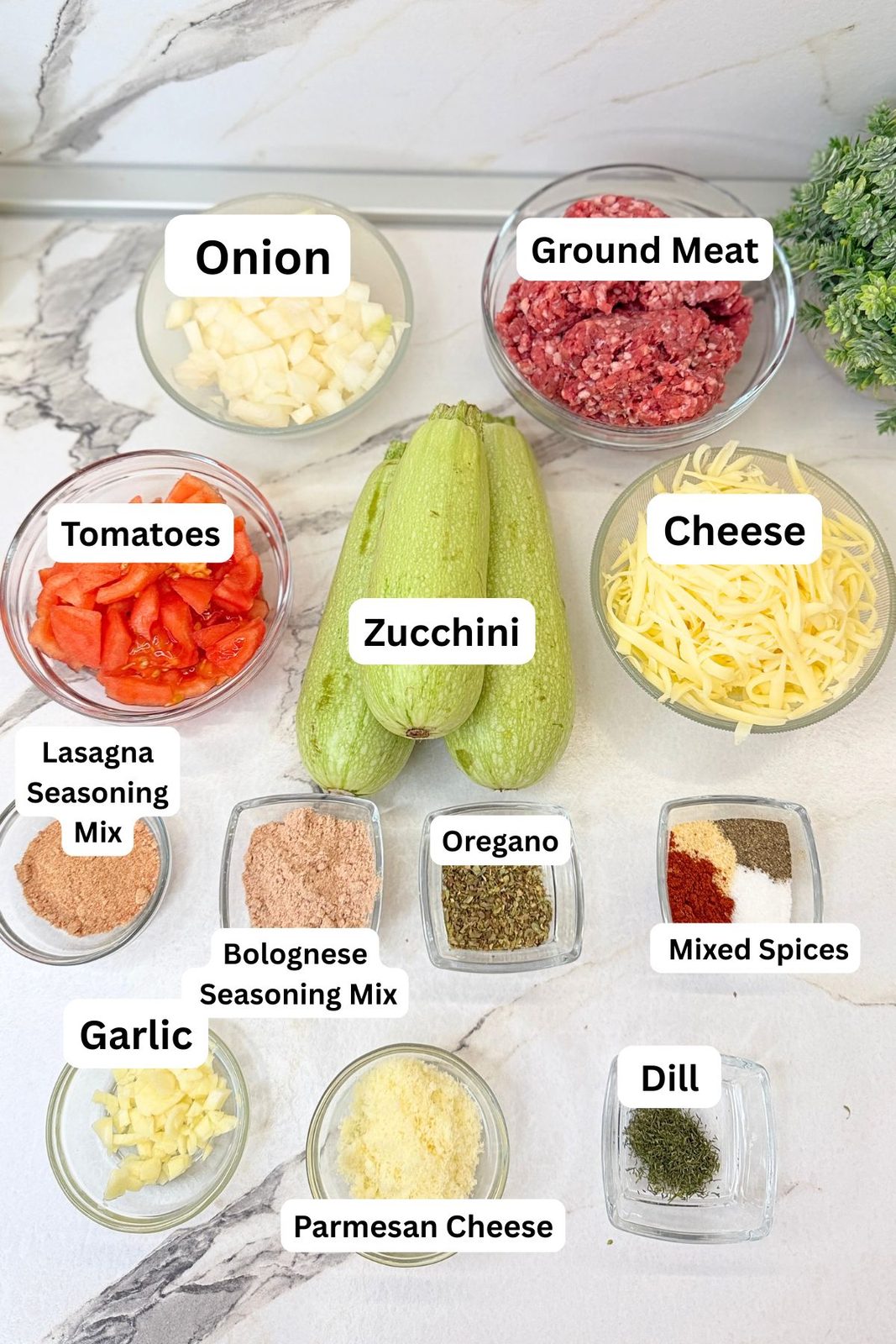 Ingredients for zucchini boats including ground beef, zucchini, tomato, onion, garlic, herbs, and cheese.