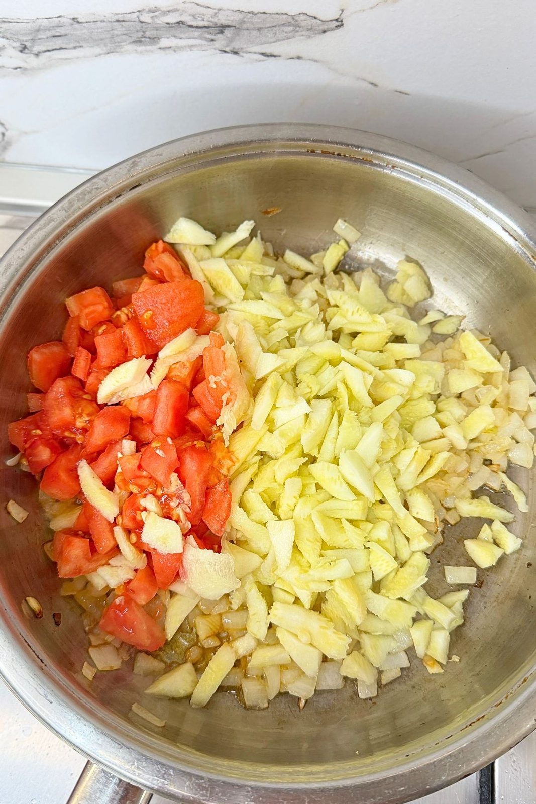 Chopped zucchini, tomato, and onion cooking in a skillet for zucchini boats filling.