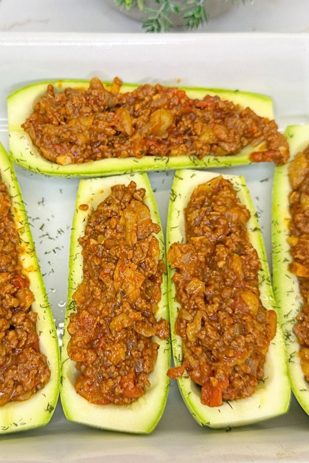 Hollowed zucchini boats filled with a seasoned ground beef and vegetable mixture.