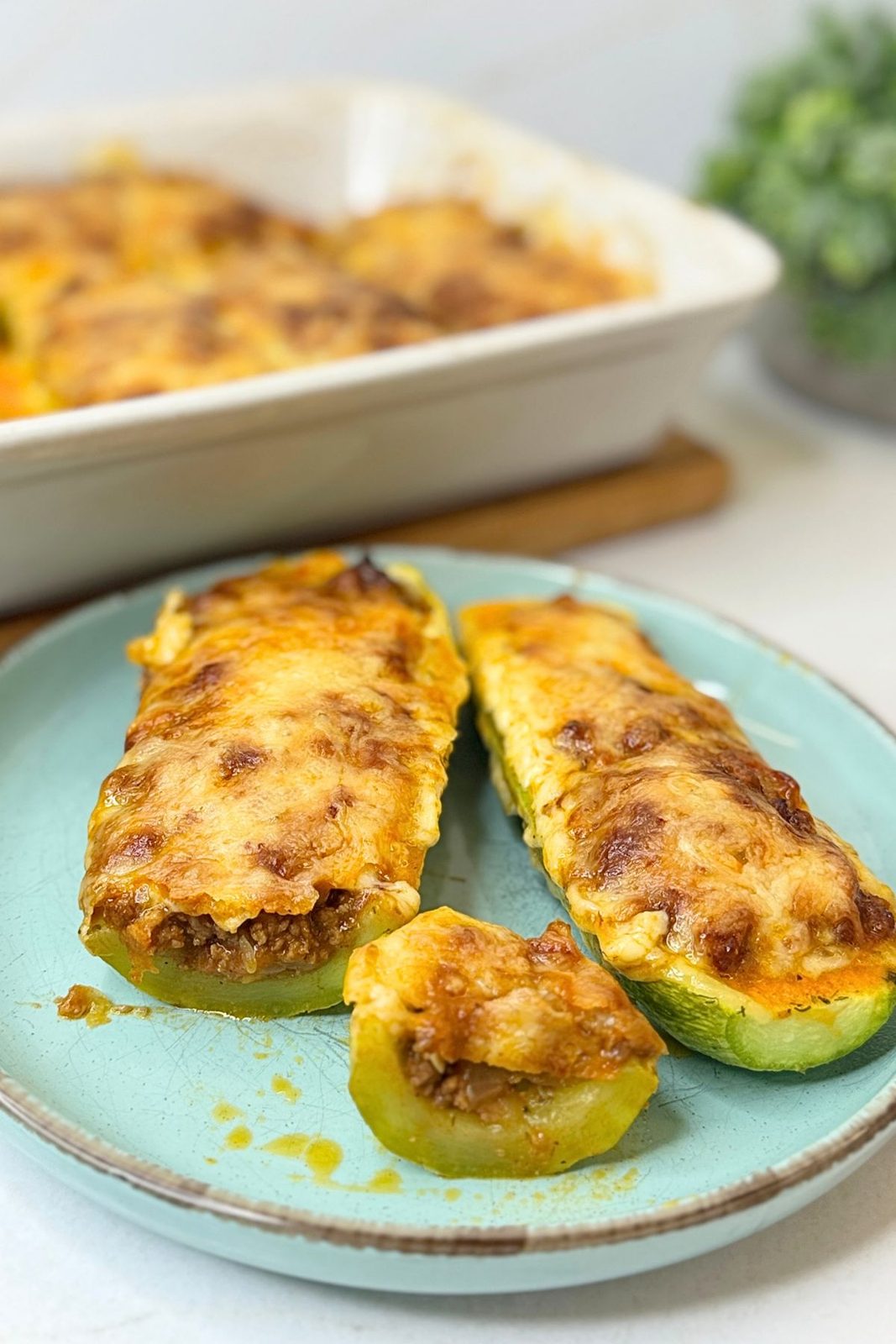 Stuffed zucchini boats with ground beef and melted cheese served on a blue plate.