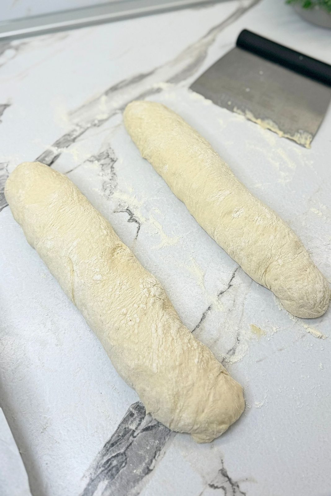 Two rustic homemade bread loaves shaped on a floured surface