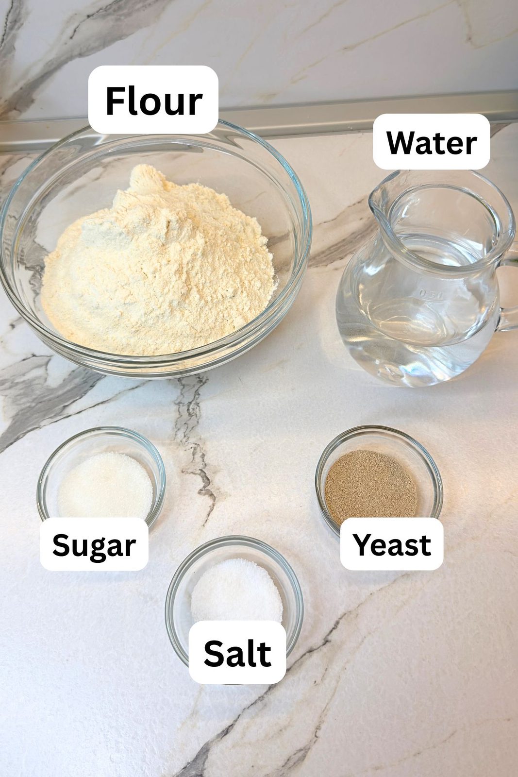 Five simple ingredients for rustic homemade bread recipe including flour, water, yeast, sugar, and salt